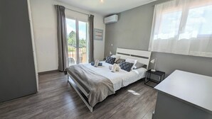 Un dormitorio moderno con una cama grande, una mesita de noche pequeña y vistas al exterior a través de un ventanal corredero.