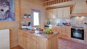 Cocina de cabaña de madera con una isla central, armarios de madera, salpicadero de azulejos y un ventanal grande.