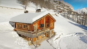 Una cabaña de madera con porche, rodeada de montañas nevadas.
