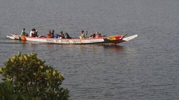 A boat with passengers on a calm body of water, surrounded by greenery.