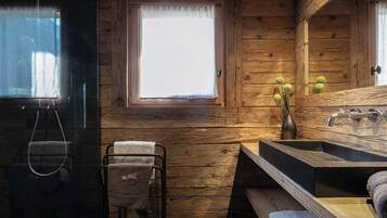 Baño de cabaña de madera con ventana, lavamanos y perchero.