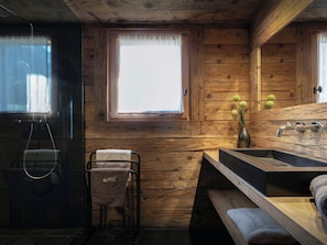Baño de cabaña de madera con ventana, lavamanos y perchero.