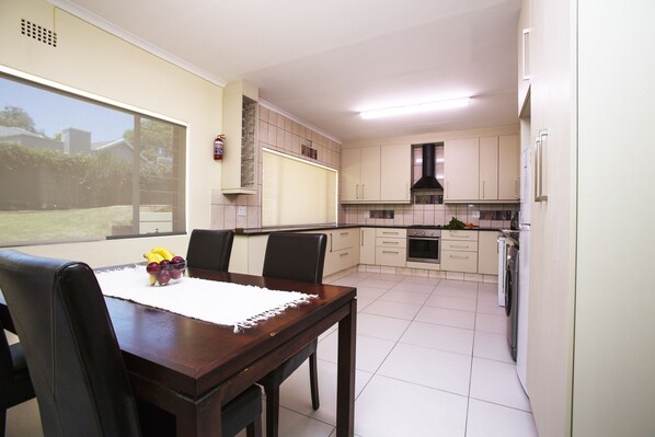 A modern kitchen with white cabinets, a dining table with chairs, and a view of the outdoors.