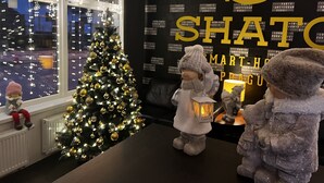 A Christmas tree with lights and ornaments, a wall with large golden letters, and two figurines on a table. -  Grand Petit Hotel (Prague)