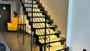 A modern staircase with a black railing and wooden steps, leading to an upper floor. -  Grand Petit Hotel (Prague)