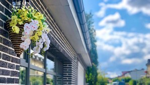 A building with a brick facade and a hanging flower arrangement. -  Grand Petit Hotel (Prague)