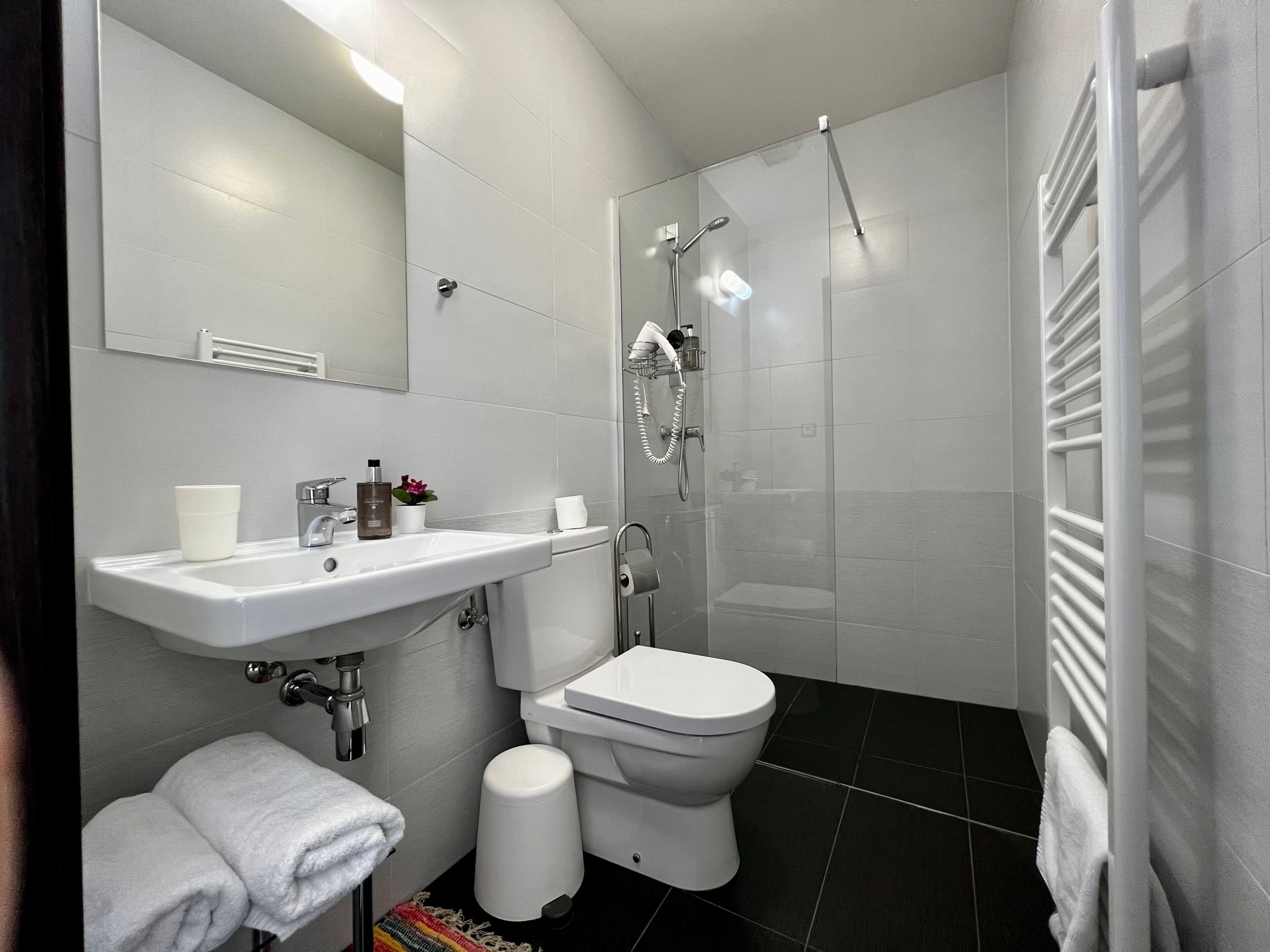 A modern bathroom with a white sink, toilet, and shower.