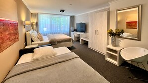 A modern hotel room with two beds, a desk, a TV, and a large mirror. -  Grand Petit Hotel (Prague)
