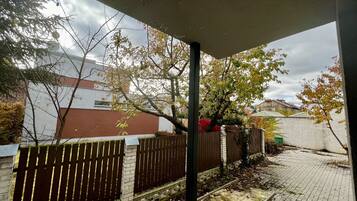 Un espacio al aire libre techado con pared de ladrillo, cerca de madera y sendero pavimentado.
