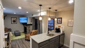 Une cuisine moderne dotée de plans de travail en granit, d’une cuisinière encastrée et de luminaires suspendus.