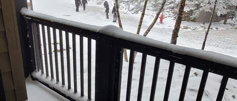 A snow-covered outdoor area with a metal bench and a table, surrounded by a railing.