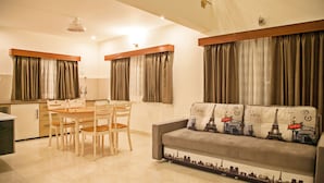 A modern living room with a sofa, dining table, and chairs. - Graces Resort (Sehore)