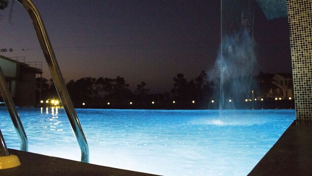 A nighttime pool area with a water feature and a metal ladder. - Graces Resort (Sehore)