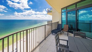 Un balcón con vistas al océano y a la playa, amueblado con sillas y una mesa.