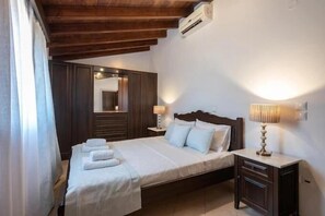 Un dormitorio con cama, mesitas de noche, un espejo y un aire acondicionado.