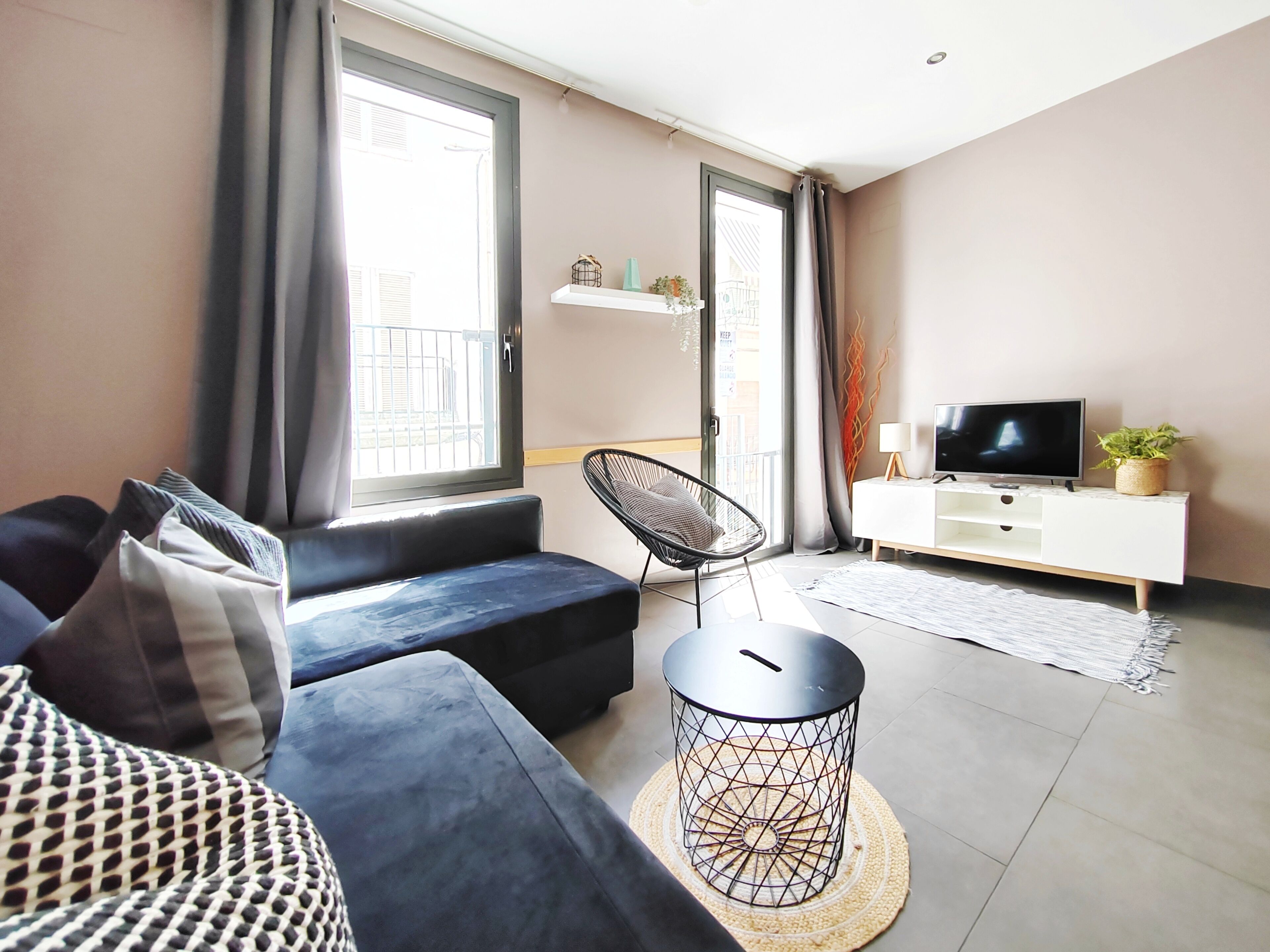 A modern living room with a sofa, a chair, a TV, and a small side table.