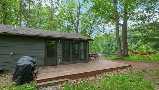 Une cabane avec une terrasse, un barbecue couvert et un hamac.