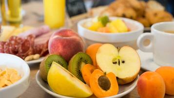 A breakfast table with various fruits, pastries, and a coffee cup.
