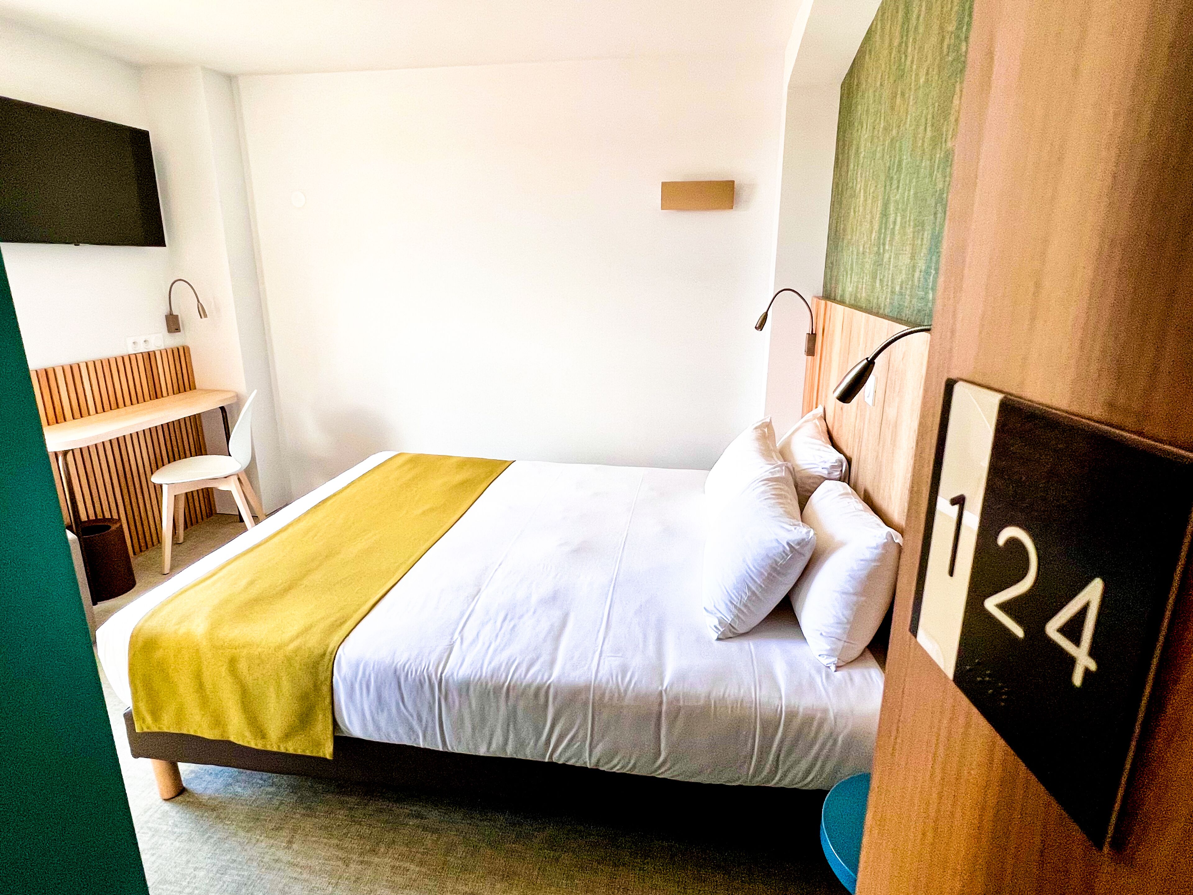 A hotel room with a bed, a desk, and a chair.