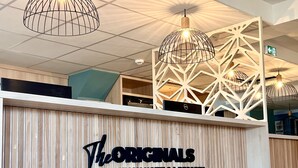 A reception desk with a sign reading "The Originals Human Hotels & Resorts".