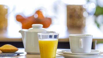 A breakfast setting with a glass of orange juice, a white mug, and a teapot on a table.