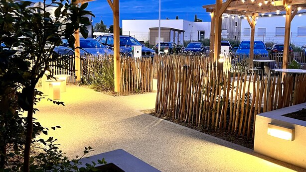 An outdoor parking area with wooden pergolas and a bamboo fence.