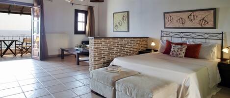 Un dormitorio con chimenea de piedra, cama con ropa de cama blanca y vistas al exterior.