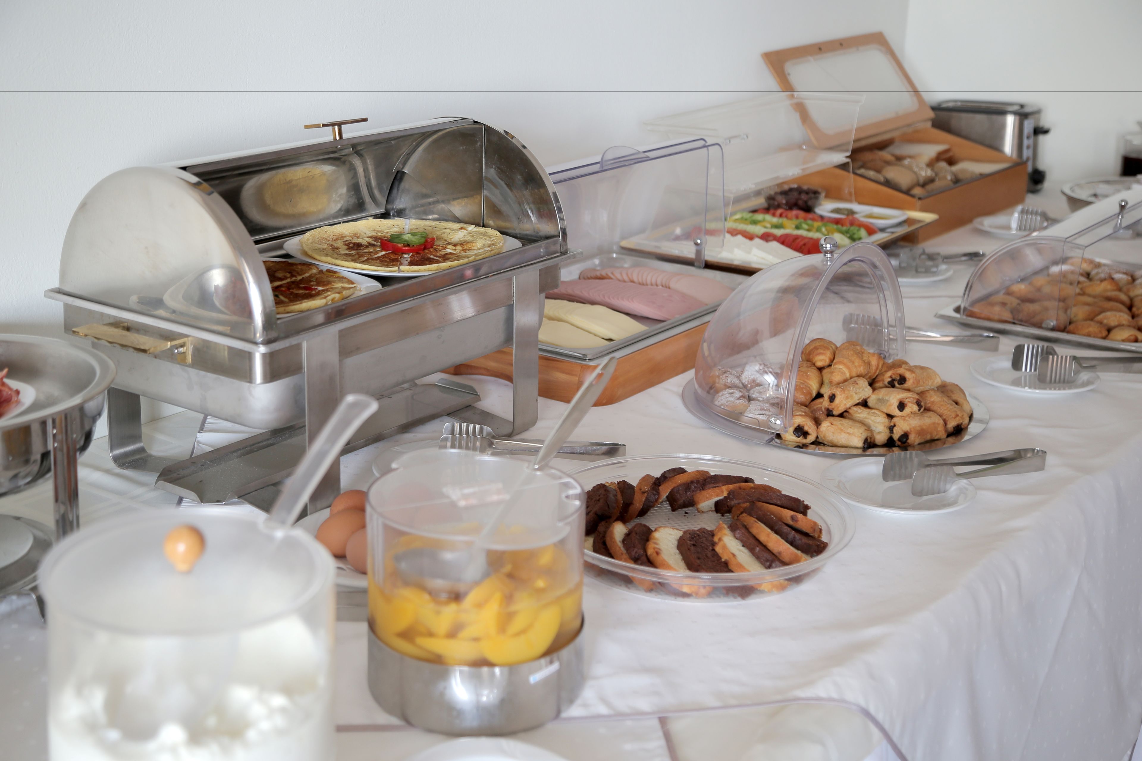 A buffet with various food items including pastries, fruits, and a hot food station.