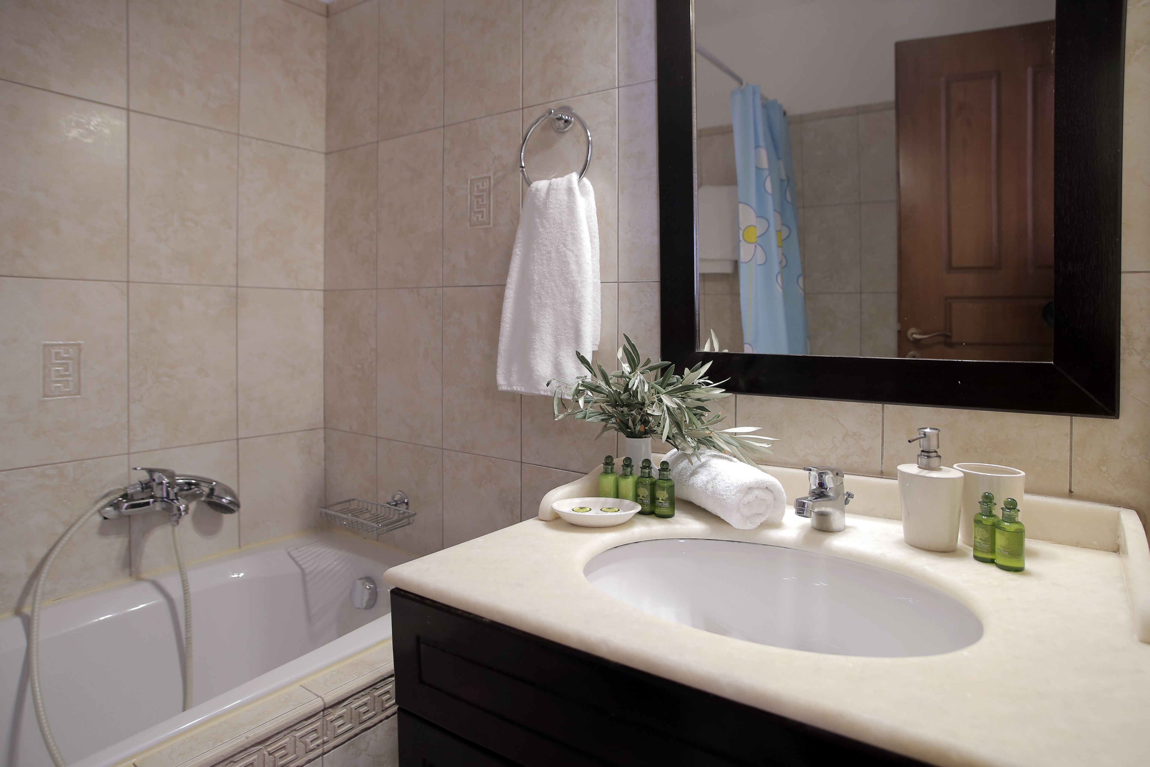 A bathroom with a bathtub, a sink with toiletries, and a mirror.