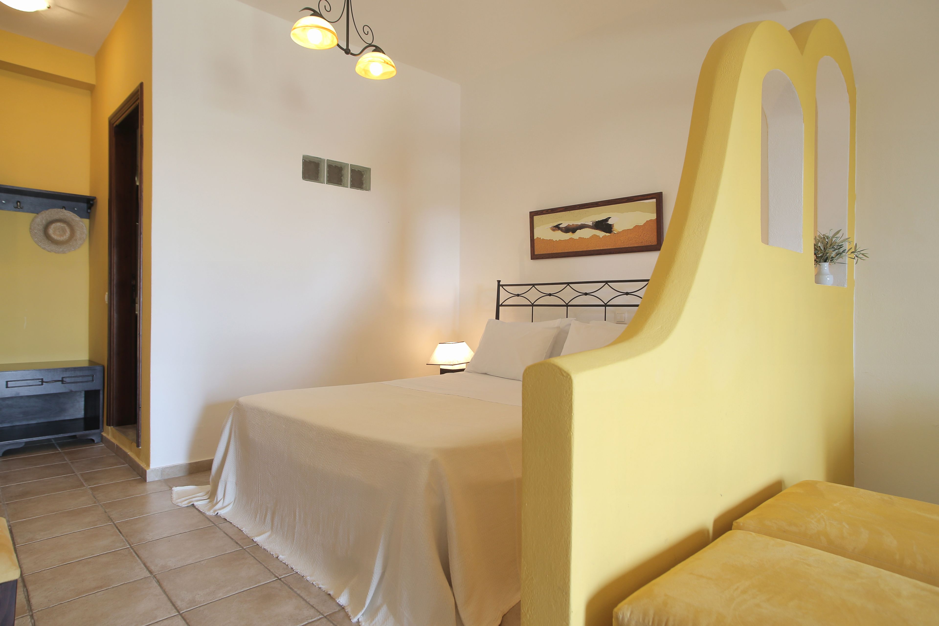A bedroom with a bed, a bedside lamp, a small table, and a wall-mounted picture.