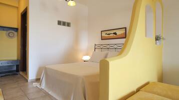 Quarto com cama, luminária de cabeceira, mesinha e quadro na parede.
