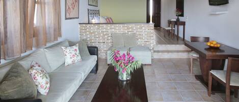 Una sala de estar con sofá, mesa de centro y comedor con sillas y una mesa.