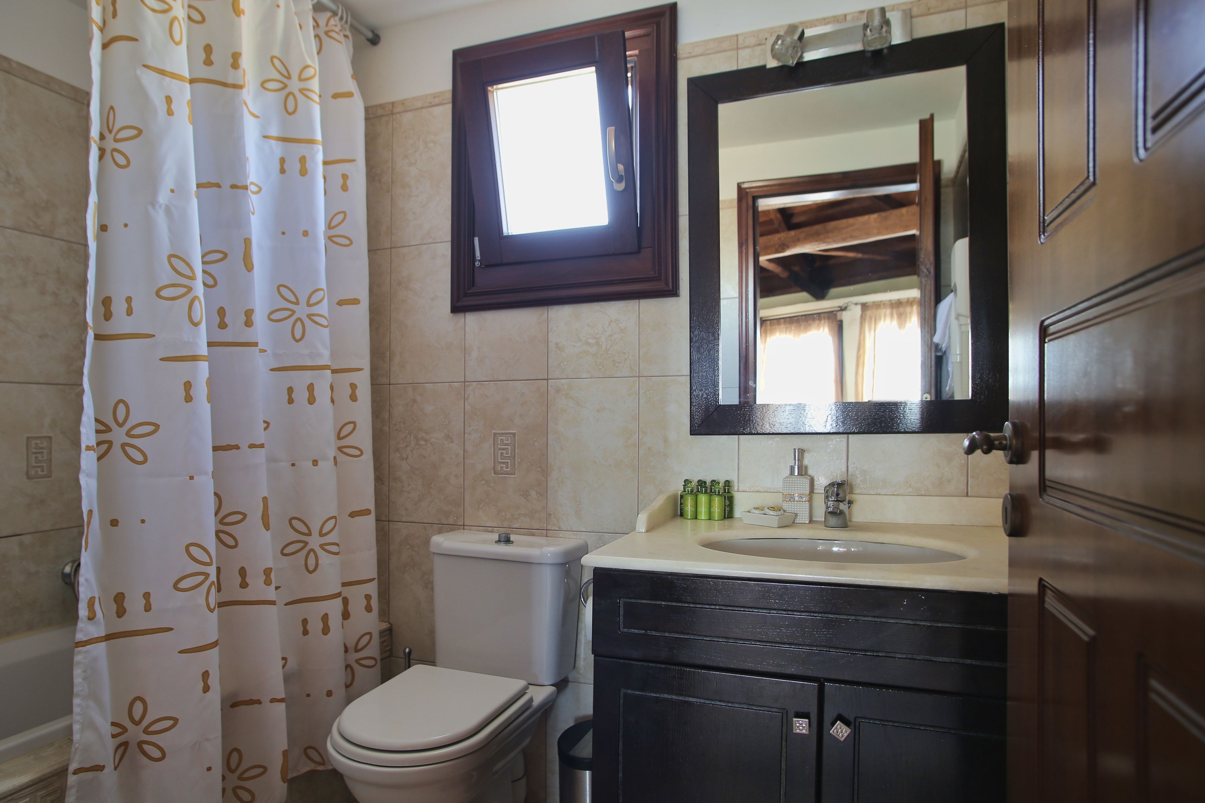 Un baño con inodoro, lavamanos, espejo y cortina de ducha.