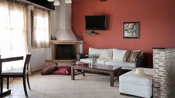 Una sala de estar con chimenea, un sofá, una mesa de centro y un televisor montado en la pared.