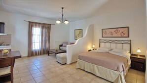 A bedroom with a bed, bedside tables, a desk, and a chair. - Yalis Hotel (Alonissos)