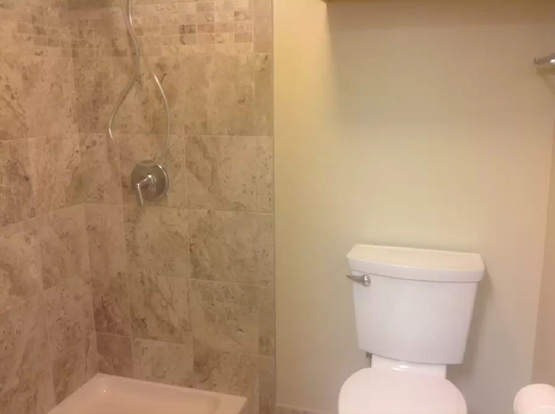 Uma casa de banho com chuveiro e sanita.