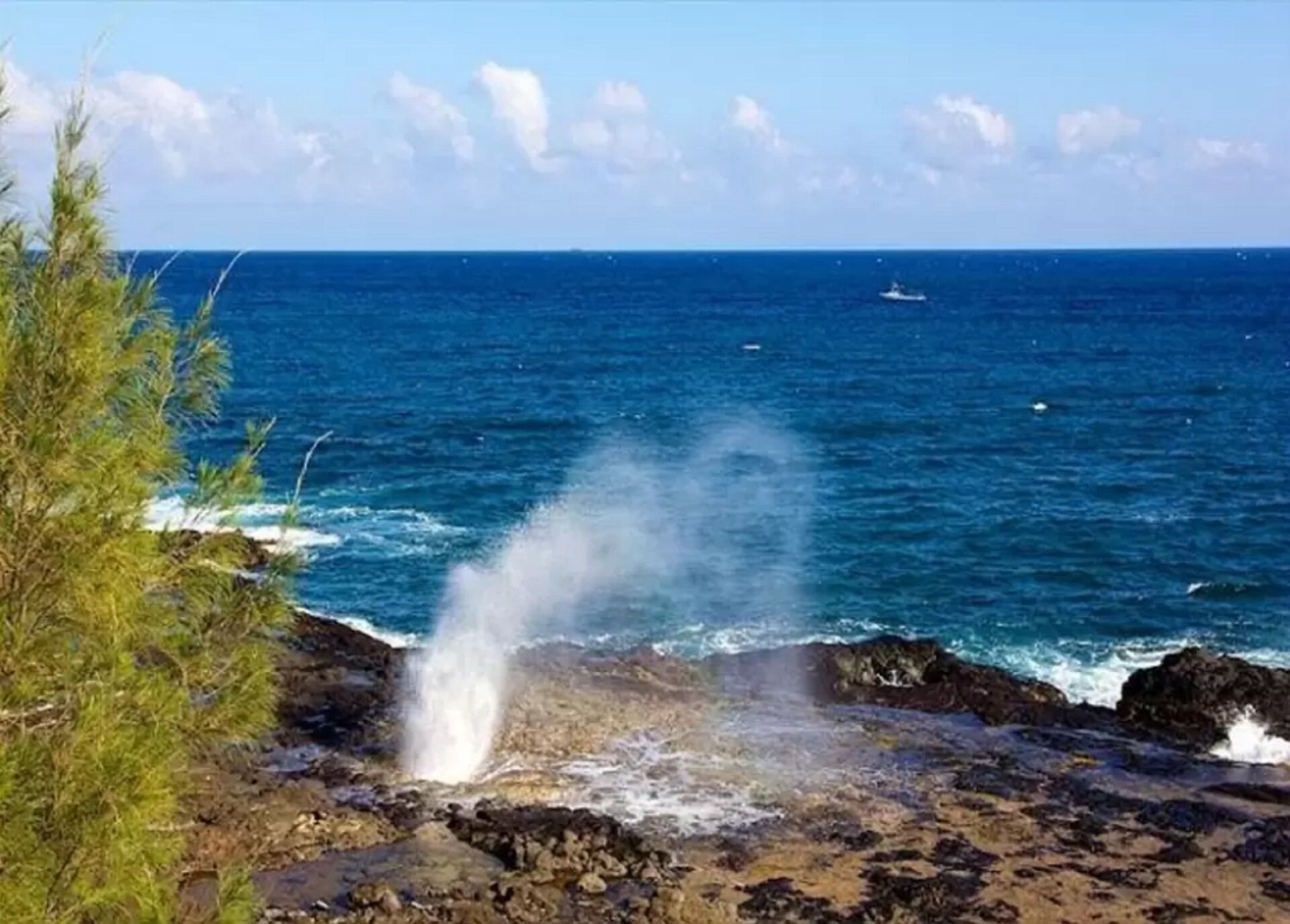 Uma paisagem costeira com um trecho de costa rochosa, ondas do oceano e céu claro.