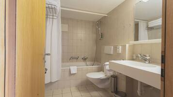 Un baño con bañera, inodoro, lavabo y espejo.