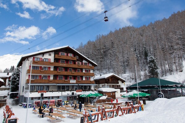 A multi-story hotel with outdoor seating and ski equipment rentals. - The Larix -Ski in, Ski out (Saas-Fee)