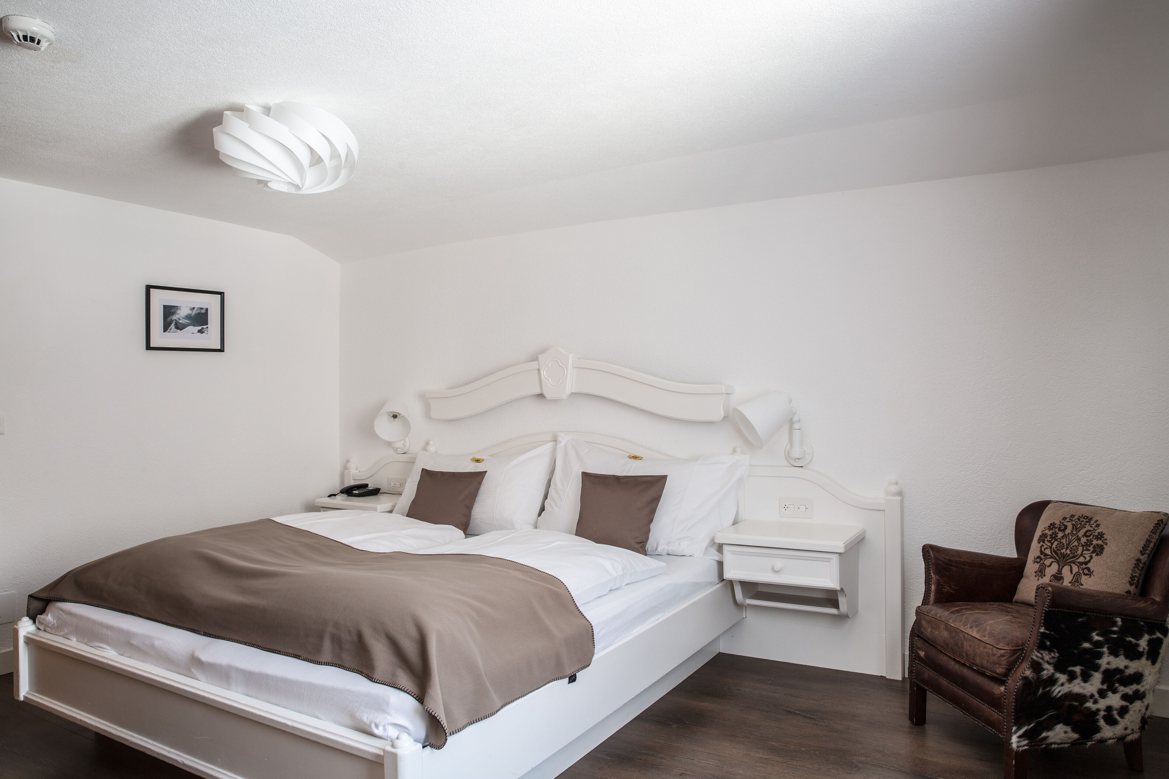 Une chambre à coucher bien rangée, avec un lit, une table de chevet, une lampe et une chaise.