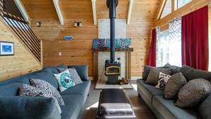 A cozy cabin interior with two sofas, a fireplace, and wooden walls. - Island house located on Stretch Island close to Fair Harbor (Grapeview)