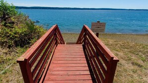 A wooden boardwalk leading to a body of water with a sign indicating private access and caution to use handrails. - Island house located on Stretch Island close to Fair Harbor (Grapeview)