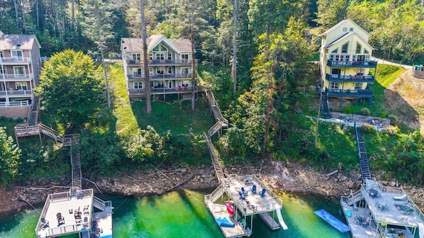 A multi-story hotel with balconies, connected by a wooden bridge over a river.