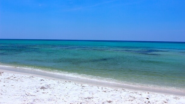 Een strand met helder turquoise water en wit zand.