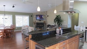 Enjoy family meals in this kitchen with a large island, stone fireplace, and flat-screen TV.