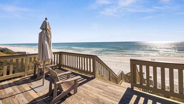 Eine Holzterrasse mit Blick auf den Strand und das Meer.