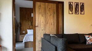 Una stanza con un'armadiatura in legno, un divano grigio e un letto con biancheria bianca.