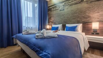 Una habitación de hotel con una cama grande, cortinas azules y un mural de un puente en la pared.