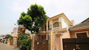 Une rue résidentielle bordée de maisons, avec une entrée fermée par un portail et un grand arbre.