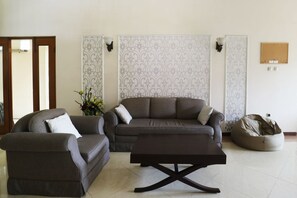 Sala de estar con sofá, sillón y mesa de centro, un panel decorativo y un tablón de anuncios.